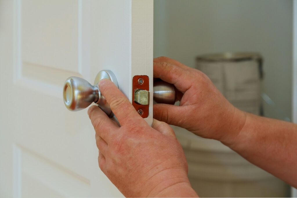 Closeup of a professional locksmith installing or repairing a new deadbolt lock on a house door after Unlocking his house